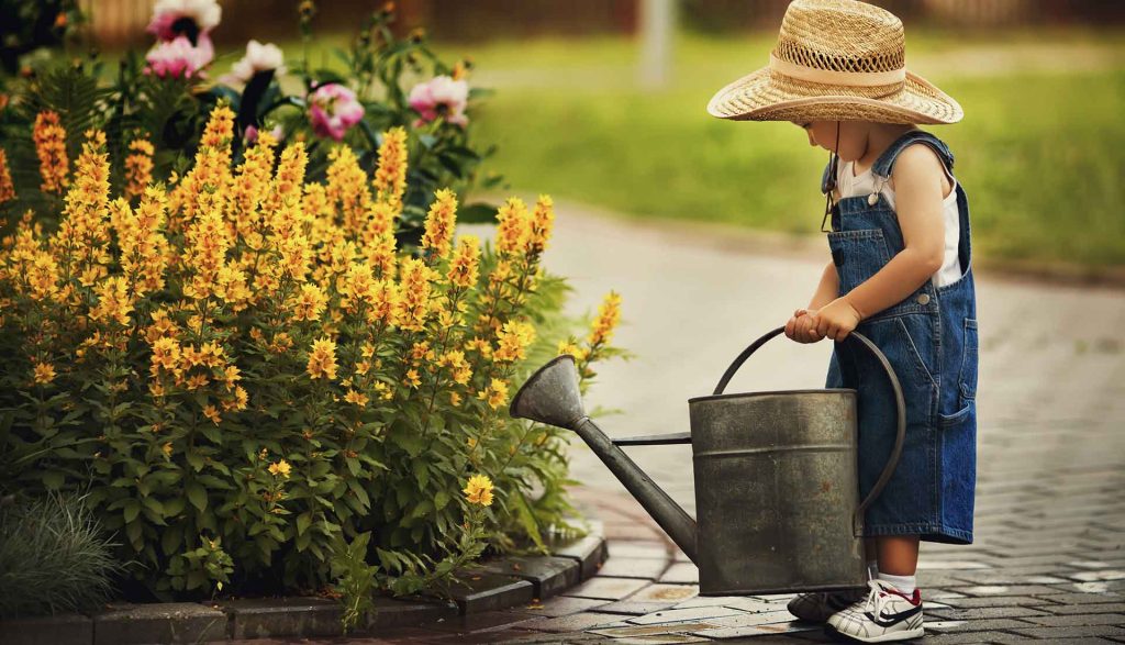 girl watering flowers with a watering can